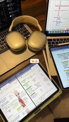 an open laptop computer sitting on top of a wooden desk next to a pair of headphones