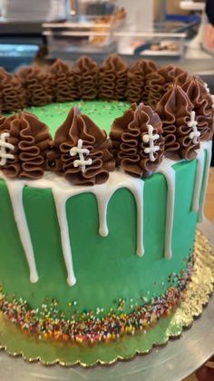 a green cake with white icing and chocolate decorations on it's top, sitting on a table