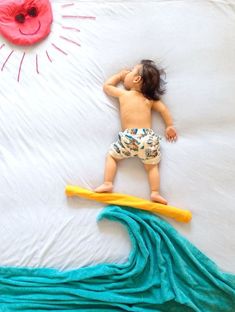 a small child laying on top of a surfboard next to a pink donut