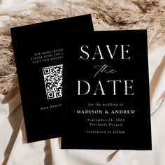 two black wedding save the dates cards on a white bed sheet with fur in the background