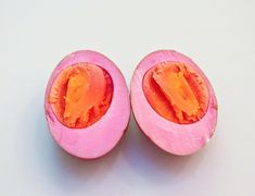 two halves of a pink fruit with one cut in half and the other partially open