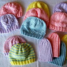 several knitted hats are arranged on a white tablecloth, one is blue and the other is pink