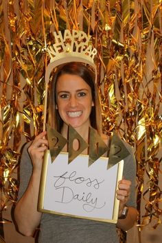 a woman holding up a sign that says happy birthday with a crown on her head