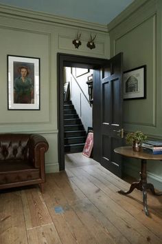 a living room with a brown leather chair and wooden flooring next to a staircase