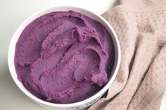 a white bowl filled with purple food on top of a pink towel next to a cloth