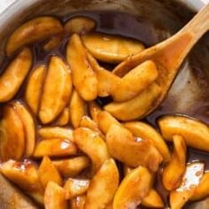 some food is being cooked in a pot with a wooden spoon and sauce on the side