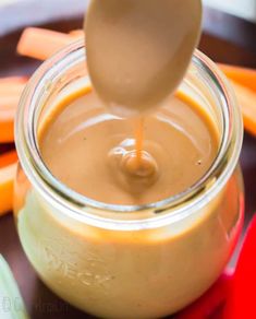 a spoon is pouring peanut butter into a jar