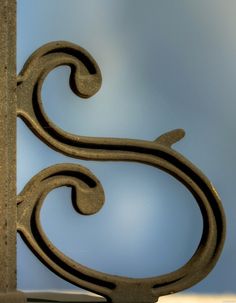 an ornamental iron design on the side of a building with blue sky in the background