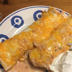 two enchiladas on a blue and white plate with a fork next to it