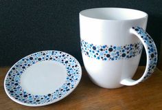 a coffee cup and saucer sitting on a wooden table next to a black wall