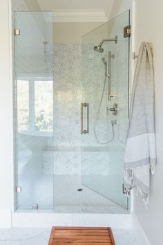 a walk in shower sitting next to a wooden bench on top of a tiled floor