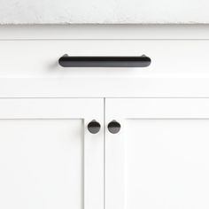 a white cabinet with black handles and knobs