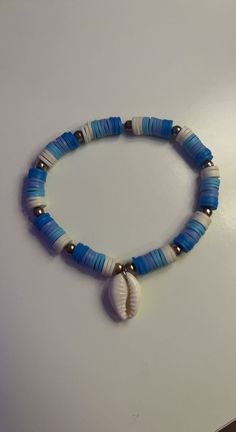 a blue and white beaded bracelet with a seashell charm hanging from it's end