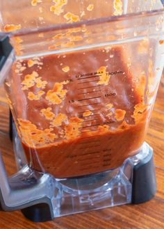 a blender filled with brown liquid on top of a wooden table