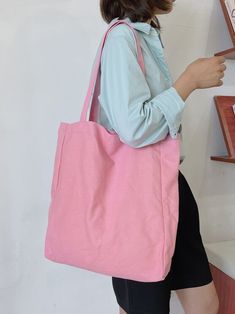 a woman holding a pink tote bag in her right hand and looking at it