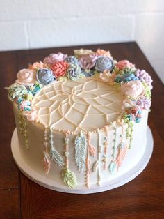 a cake decorated with flowers and feathers on a wooden table top, ready to be eaten