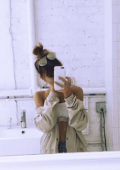 a woman taking a selfie in front of a bathroom mirror with her cell phone