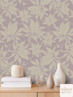 a table with two vases on it and a wallpapered background behind it