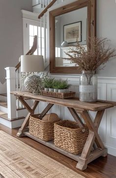 a wooden table with baskets under it and a mirror on the wall in front of it