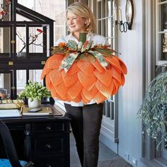 a woman is walking down the hallway carrying a large pumpkin decoration on her back and holding it in one hand