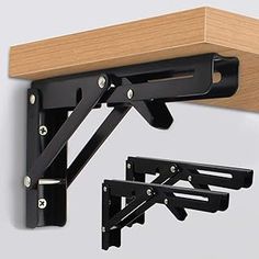 a wooden shelf with two black brackets attached to the top and one is holding a pair of scissors