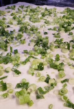 chopped green onions are being prepared on a baking sheet