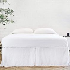 the bed is made with white linens and has two pillows on top of it