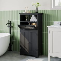 a white bath tub sitting next to a wooden cabinet in a green and white bathroom