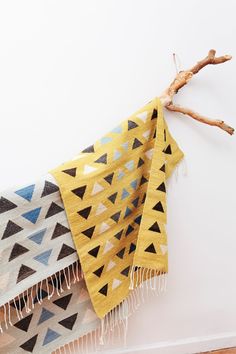 a yellow and black blanket hanging from a tweet on a wall next to a branch