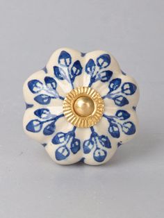 a blue and white flower shaped object with a gold center on it's side