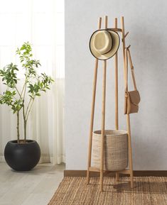 a hat and coat rack in front of a white wall with a potted plant