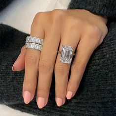 a woman's hand with two rings on her fingers and an engagement ring in the middle