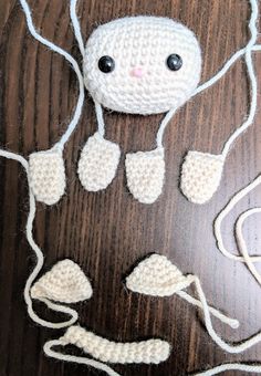 a crocheted white object with black eyes and headphones attached to it on a wooden surface