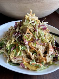 a white plate topped with a salad next to a bowl