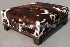 the footstool is made out of wood and cow print fabric with studding