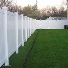 a white fence is lined with green grass