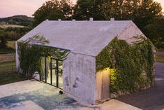 an old building with vines growing on it's roof and side walls, next to a road