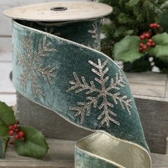 a green ribbon with snowflakes on it next to holly wreaths and other holiday decorations