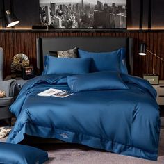 a bed with blue comforters and pillows in a hotel room next to a gray chair