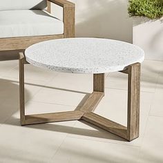 a white table sitting on top of a tiled floor next to a chair and couch