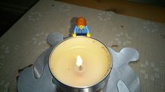 a candle that is sitting on top of a metal tray with a toy figure in it