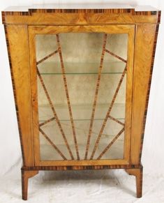 an old wooden cabinet with glass doors and wood trimmings on the top shelf