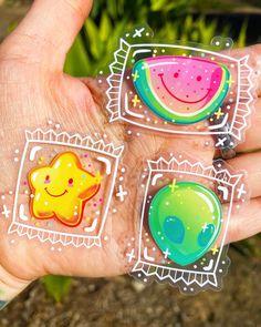 three stickers in the palm of someone's hand that has watermelon, star and moon designs on them