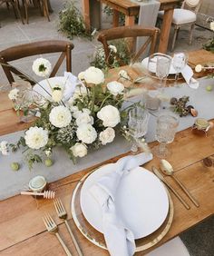 the table is set with white flowers and silverware