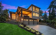 a large house with lots of windows and grass in the front yard at night time