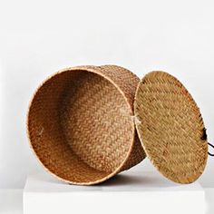 two round baskets sitting on top of a white table next to a bottle of wine