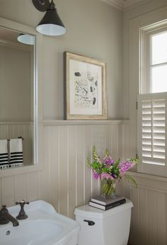 a white toilet sitting next to a sink in a bathroom under a framed art above it