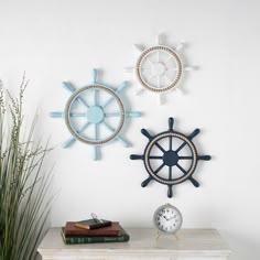 there are three clocks on the wall and one has a ship's steering wheel