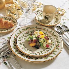 a white table topped with plates and silverware next to a cup filled with fruit