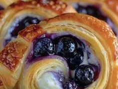 blueberry pastry rolls with icing and powdered sugar are shown in close up